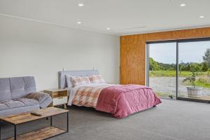 a bedroom with a bed and a couch and a window at The Little Hive in Westport