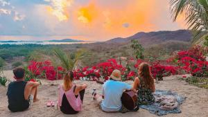 a group of people sitting on the beach watching the sunset at The Dream Eco Glamping in La Sabrosa
