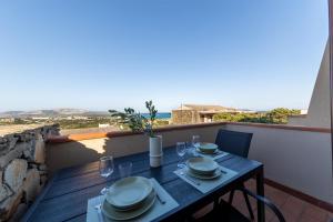 a table with plates and glasses on a balcony at L14 Appartamento Valle della Luna in Stintino