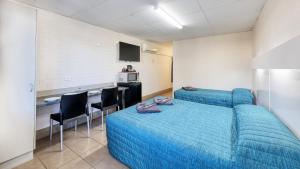 a bedroom with a blue bed and a kitchen at Motel 707 in Emerald