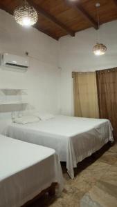 two beds in a room with white sheets and two lights at Casa Esmeralda in La Huerta +5 photos