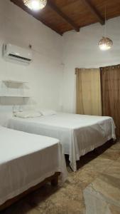 two beds in a room with white sheets at Casa Esmeralda in La Huerta