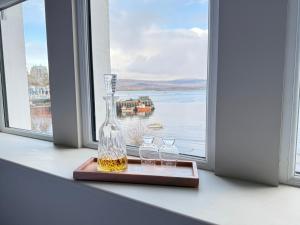 a bottle of whiskey and three glasses on a window sill at MacDonald Arms Hotel in Tobermory
