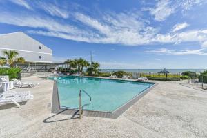 a large swimming pool with chairs and the ocean at Baca Beach Escape II in Galveston