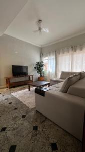 a living room with a couch and a flat screen tv at Pousada Mar de Ubatuba - Itaguá in Ubatuba
