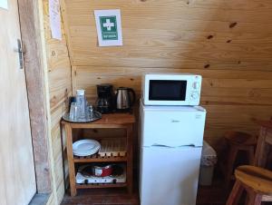 a small kitchen with a microwave on top of a refrigerator at Posada Turística Alpinas Kamba in Paraguarí
