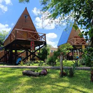 two large wooden structures in a yard with grass at Posada Turística Alpinas Kamba in Paraguarí