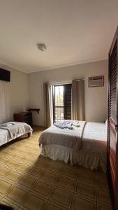 a bedroom with two beds and a window at Pousada Mar de Ubatuba - Itaguá in Ubatuba
