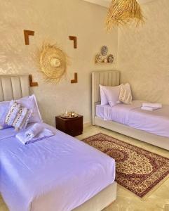 two beds in a room with purple sheets and a table at Marrakech in Marrakesh
