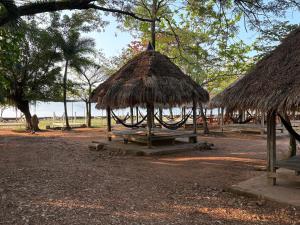 a picnic table with a straw hut and a bench at Wheelezz in Kep