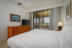 a bedroom with a large white bed and a television at Waikoloa Fairways Unit A207 Golf Ocean View 2BD 2BA in Waikoloa Village +18 photos