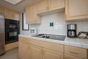 a kitchen with wooden cabinets and a counter top at Waikoloa Fairways Unit A207 Golf Ocean View 2BD 2BA in Waikoloa Village