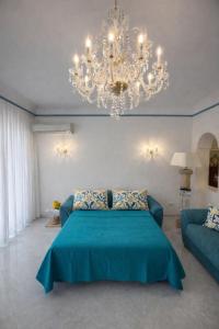 a bedroom with a blue bed and a chandelier at Panoramic Apartment Sea & Vesuvio View, Sorrento Center, COSTA DEL SOLE in Sorrento