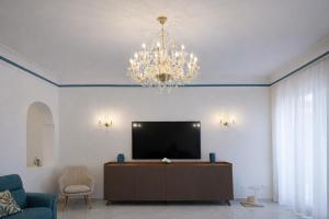 a living room with a television and a chandelier at Panoramic Apartment Sea & Vesuvio View, Sorrento Center, COSTA DEL SOLE in Sorrento