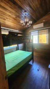a bedroom with a green bed in a wooden room at Bunkhouse Lodge in Omoa