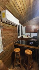 a kitchen with a counter and two stools in it at Bunkhouse Lodge in Omoa