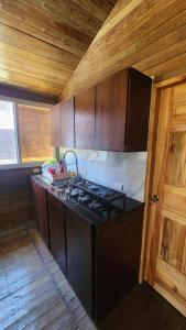 a kitchen with a stove and wooden cabinets at Bunkhouse Lodge in Omoa