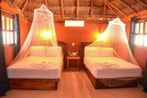 two beds in a room with mosquito nets over them at Hotel Aldea Cruzo'ob in Felipe Carrillo Puerto