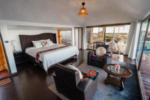a bedroom with a bed and two chairs and a table at Uros Titicaca Kurmi lodge in Puno