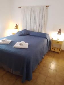 a bedroom with a blue bed with towels on it at Otto's Haus in Villa General Belgrano