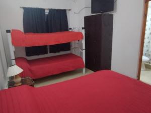 a living room with a red couch and a television at Hotel Graciela in Villa Carlos Paz +2 photos