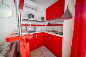 a red kitchen with a sink and red cabinets at Beau studio au coeur du Gosier in Le Gosier