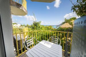 a balcony with a white table and chairs and the ocean at Beau studio au coeur du Gosier in Le Gosier