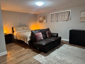 a bedroom with a bed and a leather couch at 2BR Spacious Escape Close to DC & Baltimore in Laurel