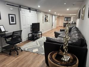 a living room with a black leather couch and a television at 2BR Spacious Escape Close to DC & Baltimore in Laurel