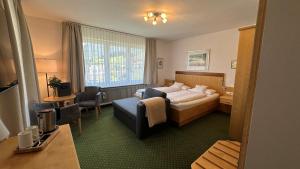 a hotel room with a bed and a chair at Hotel Steffl Garni inkl Chiemgau Karte in Ruhpolding
