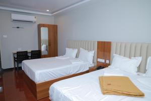 a hotel room with two beds and a mirror at Hotel Sivani in Kalakkādu