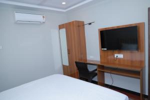 a bedroom with a bed and a desk with a television at Hotel Sivani in Kalakkādu