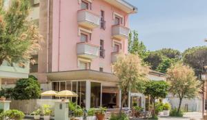 a pink building with trees in front of it at Hotel Canasta in Misano Adriatico