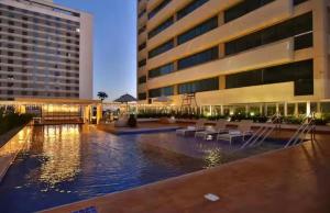 a hotel with a pool in front of a building at LUXO Premium Studio Pelinca in Campos dos Goytacazes