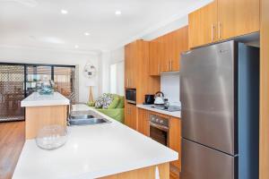 a kitchen with a stainless steel refrigerator and wooden cabinets at Echo Waves in Kiama +5 photos