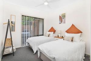two beds in a room with a window at Echo Waves in Kiama