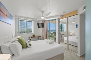 a bedroom with a large white bed and a balcony at Grand Palais Boolarong Beachside Apartments in Alexandra Headland +282 photos