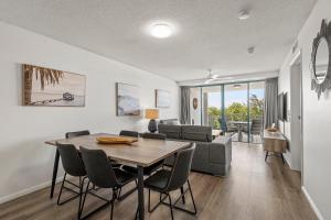 a dining room and living room with a table and chairs at Grand Palais Boolarong Beachside Apartments in Alexandra Headland