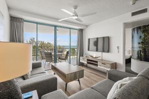 a living room with a couch and a tv at Grand Palais Boolarong Beachside Apartments in Alexandra Headland