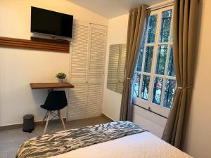 a bedroom with a bed and a tv and a window at Morada Luna Roma in Mexico City