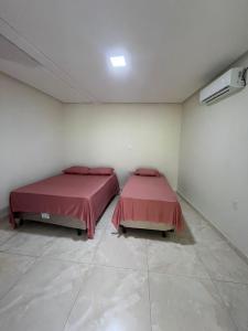 two beds in a white room with red sheets at chacara por do sol in Piranhas