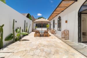 an outdoor patio with chairs and an umbrella at Chic 2BR Private Pool Villa in Canggu in Dalung
