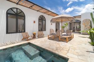 a patio with a pool and chairs and an umbrella at Chic 2BR Private Pool Villa in Canggu in Dalung
