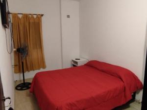 a bedroom with a bed with a red blanket at Hotel Graciela in Villa Carlos Paz +3 photos