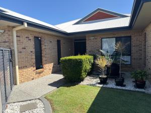 a brick house with plants in the front yard at Luxury Newport canal king suite home in Redcliffe