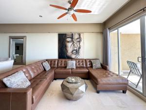 a living room with a brown leather couch and a painting at Beachfront Condo with Stunning Views Tranquil Stay in Puerto Peñasco