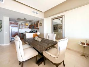 a dining room with a wooden table and white chairs at Beachfront Condo with Stunning Views Tranquil Stay in Puerto Peñasco +30 photos