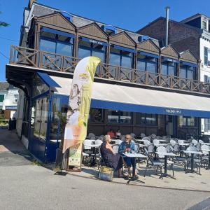two people sitting at tables in front of a building at Mado by Scoop in Le Crotoy