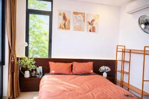 a bedroom with a bed with orange sheets and a window at Pavillon D'Hue Homestay in Hue