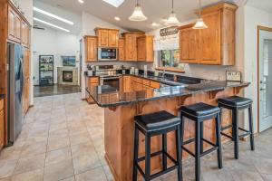 a kitchen with wooden cabinets and black counter stools at Private Riverfront Estate with Kayaks & Views in Post Falls